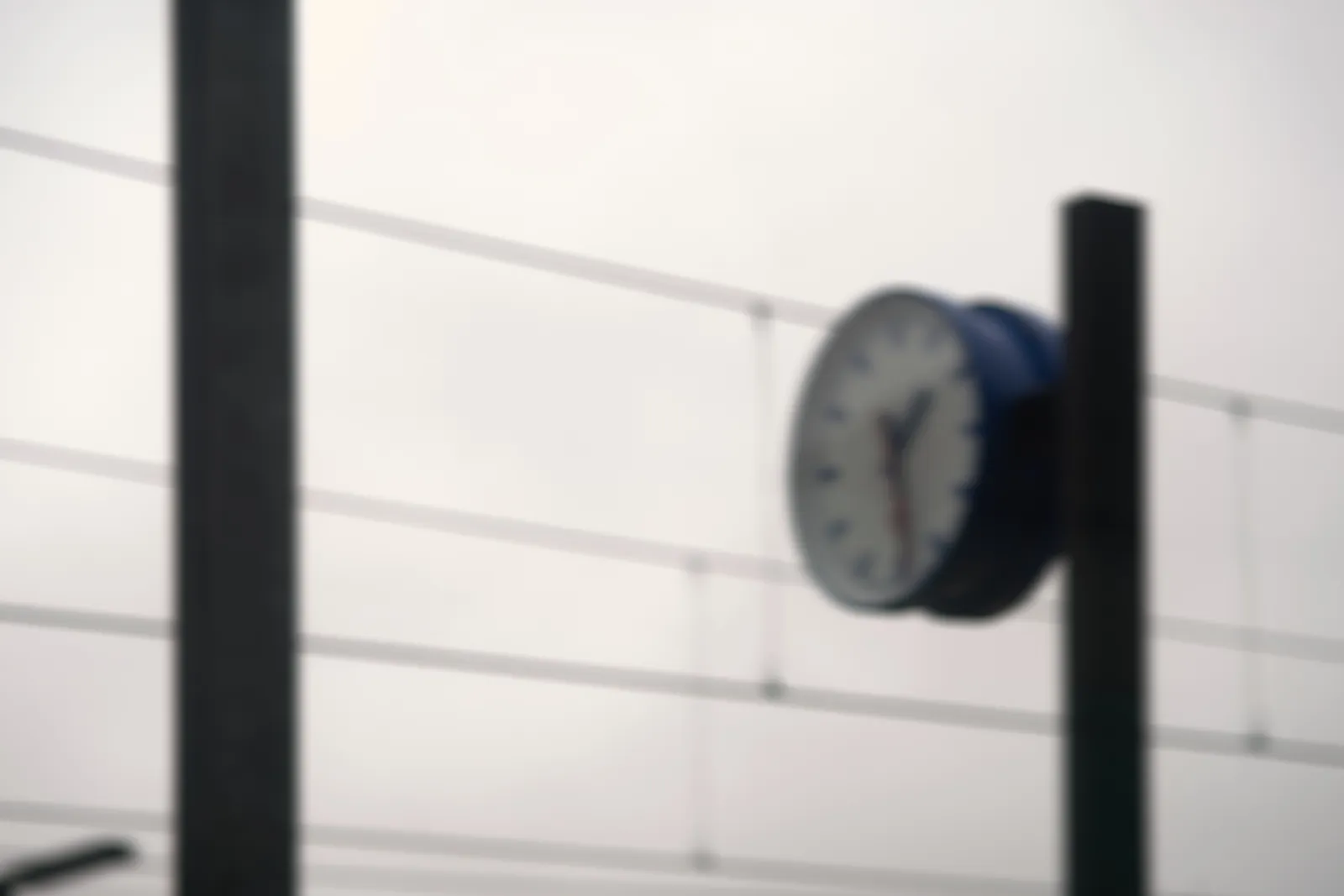 A blurry picture of a clock. It points at approximately 28 past 1.