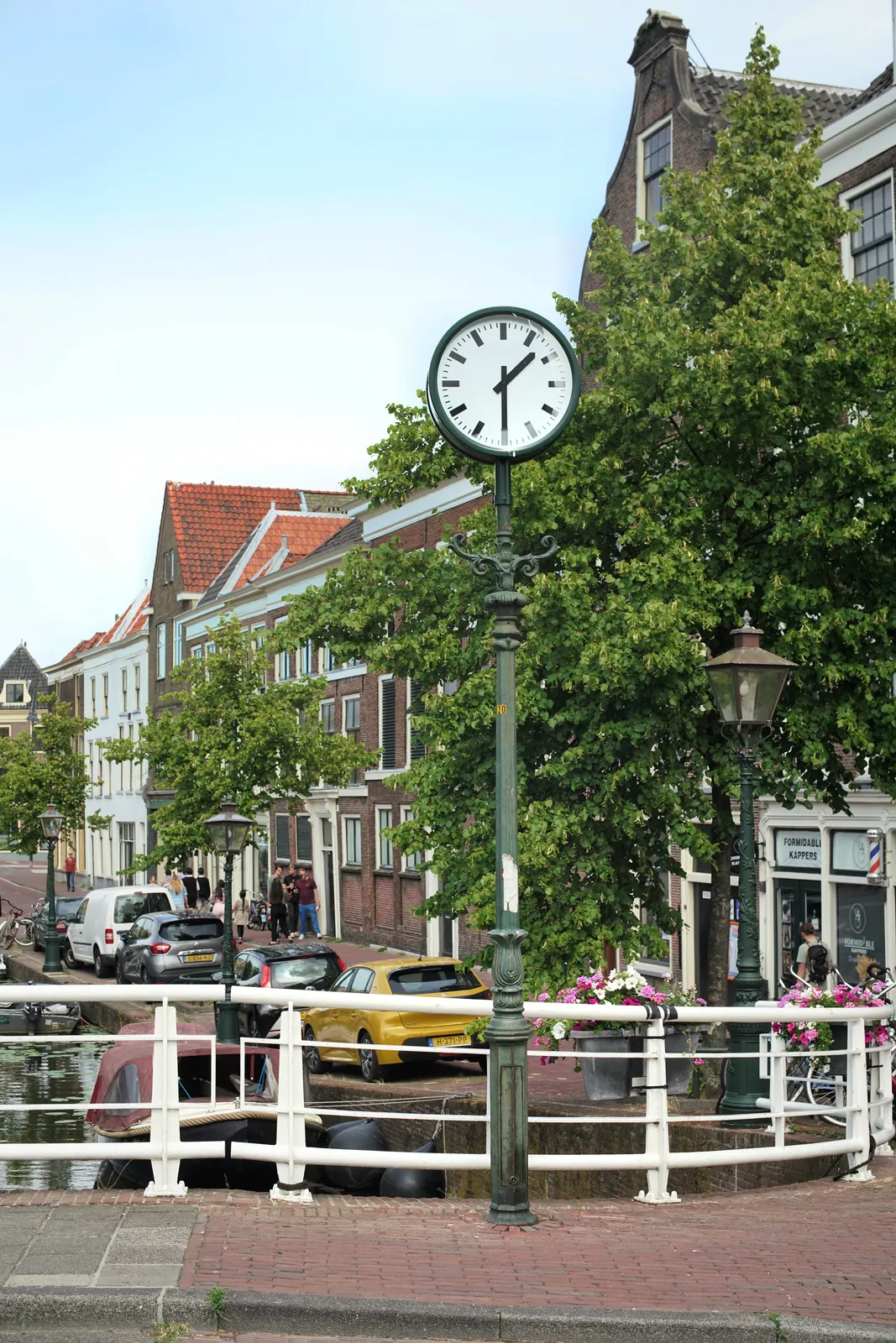 A clock on a pole on a bridge over a canal in Leiden. It points at half past one.