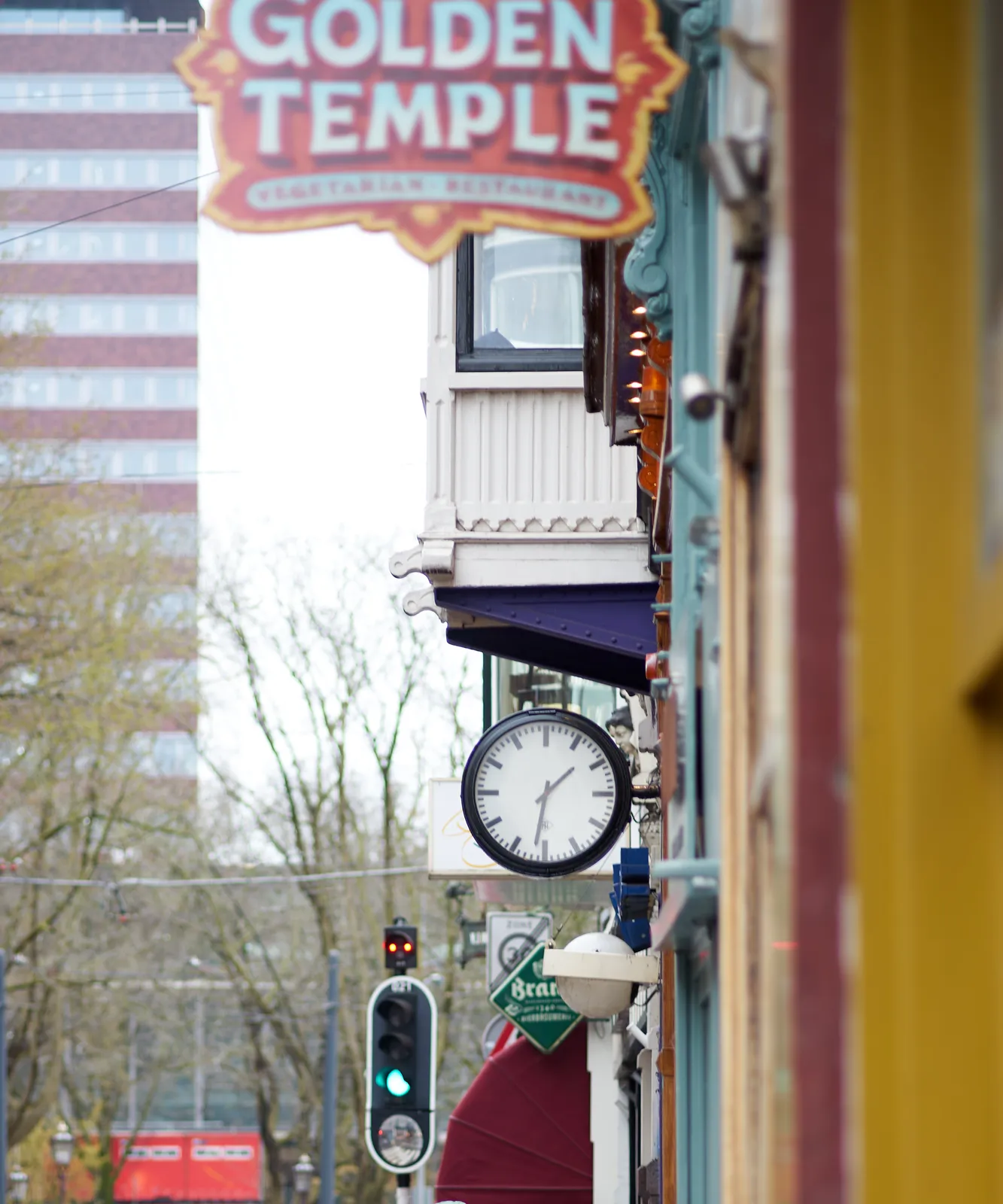 A clock attached to a colourful facade. On it it is 31 past one.
