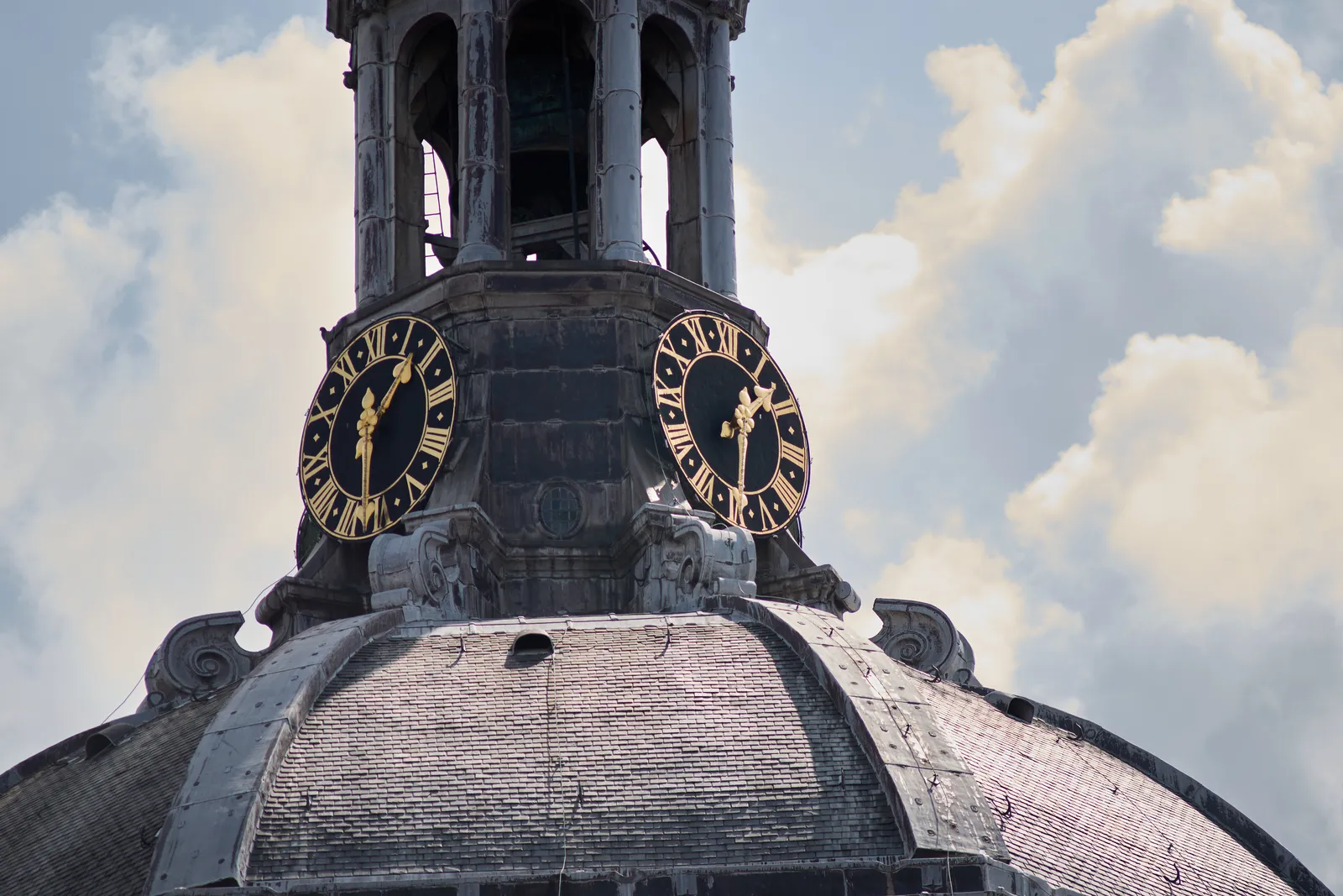 Two clocks on this tower on top of a church dome. They seem to point at approximately 28 minutes to two.