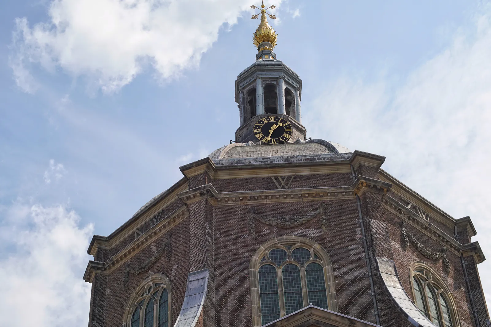 On top of a church dome there’s a little tower with a golden point and a clock. According to the clock it’s 33 past one. 