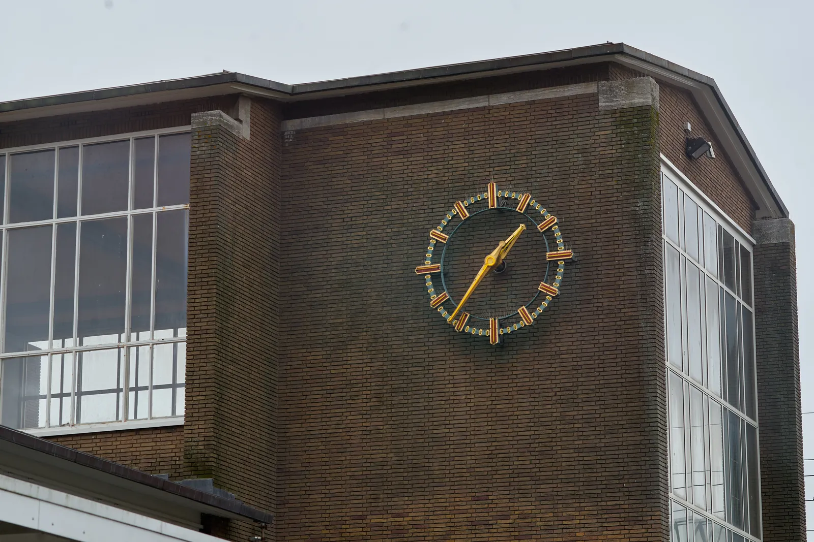 A very large clock on the facade of the old central hall of the Muiderpoort Station in Amsterdam points at 36 past one.