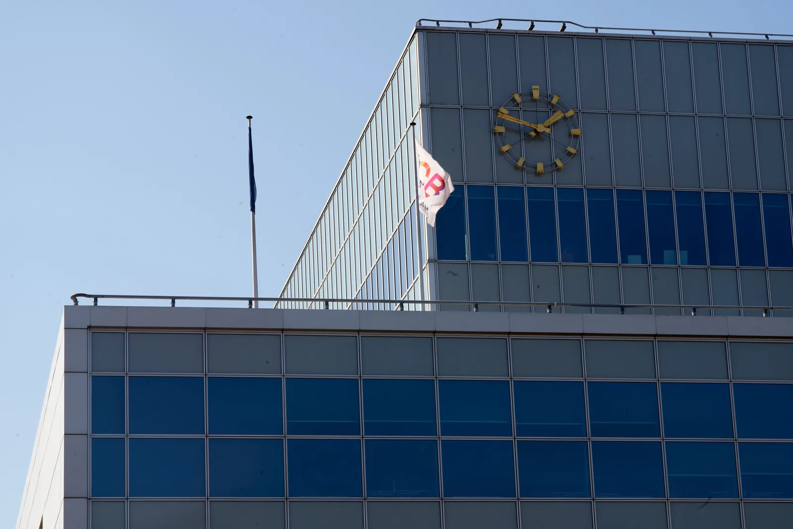 A large clock on a modernist building points at 11 minutes to two.
