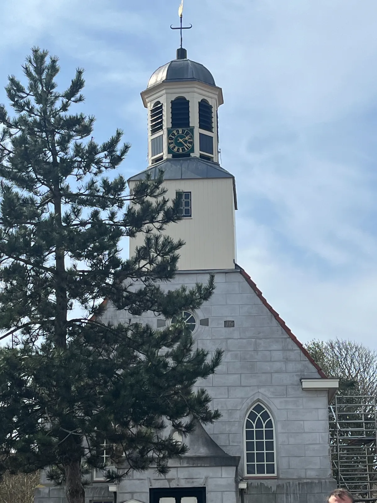 A small church with a clock on it that points at 23 minutes past 2.