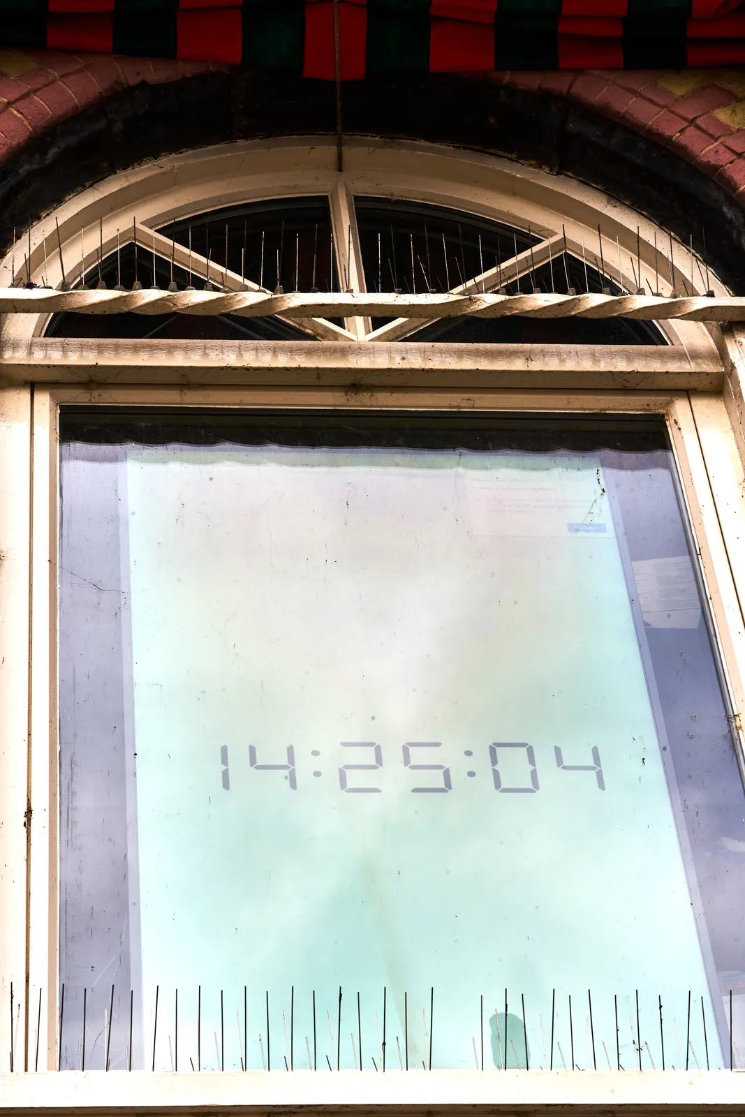 Behind a window there’s a very large digital clock that says it’s 14:25