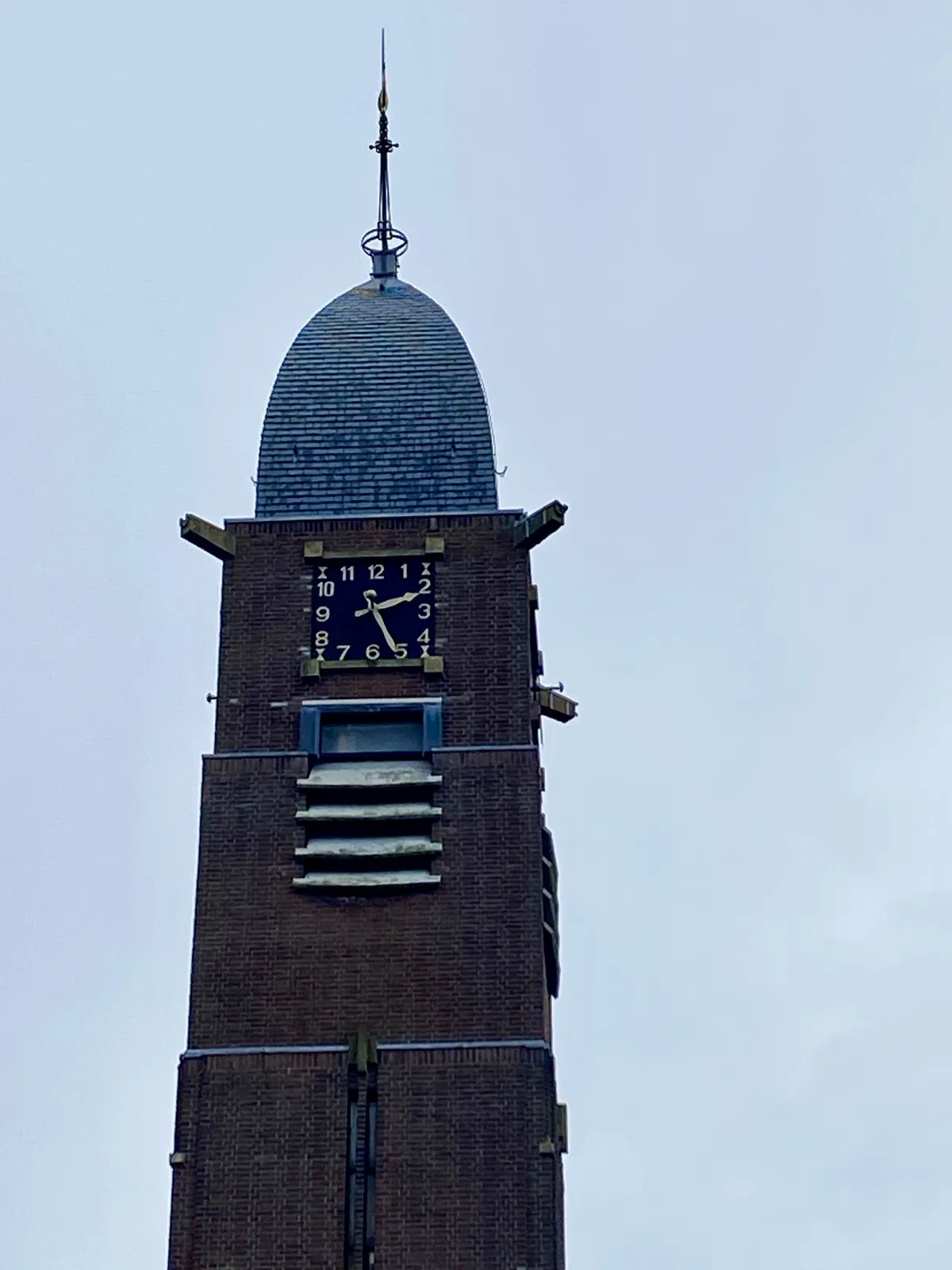 A clock on a early 20th century brick church. It points at 26 minutes past 2.