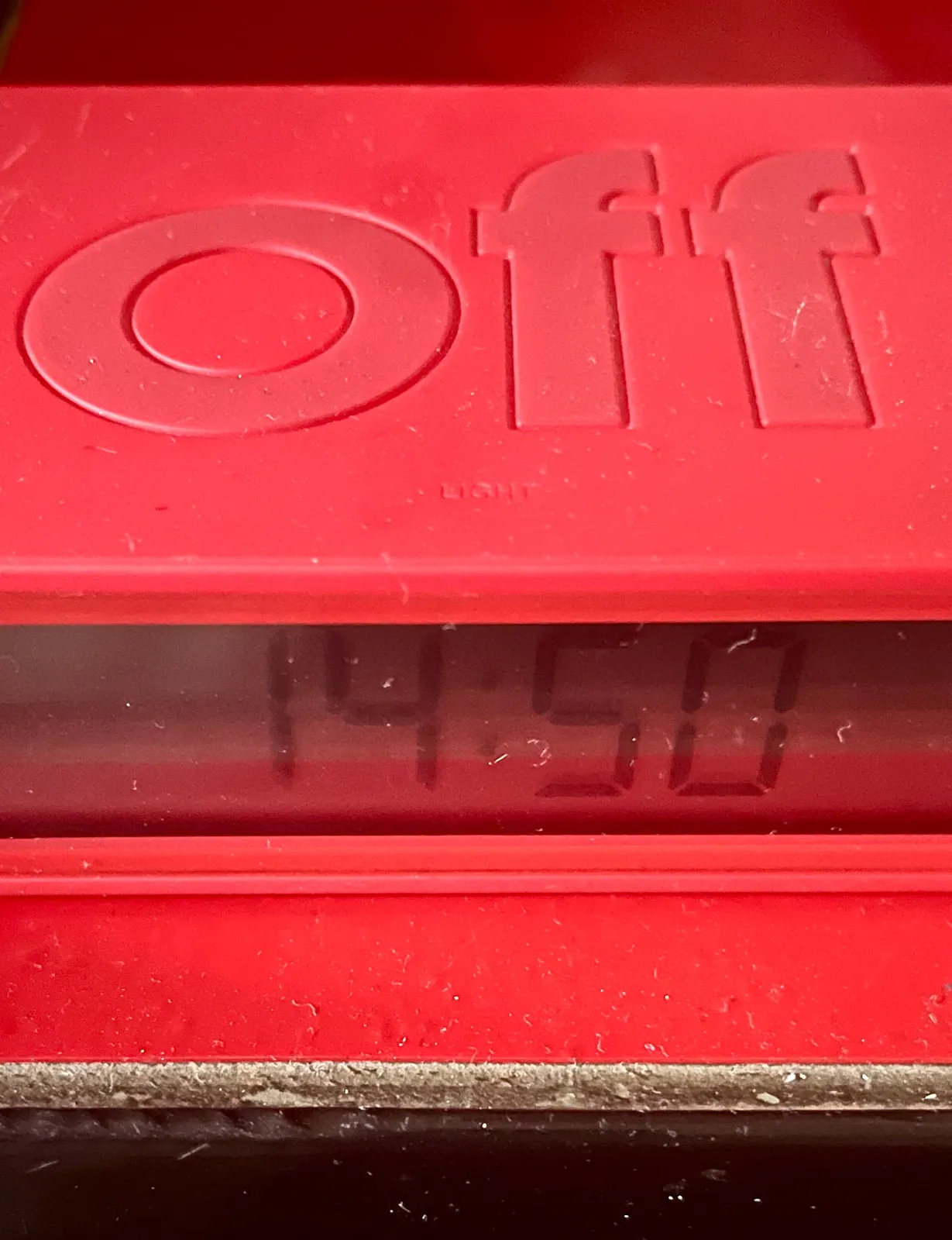 A red digital clock on a red shelf. The word Off is printed in large letters on this clock. It displays the time as 14:50.