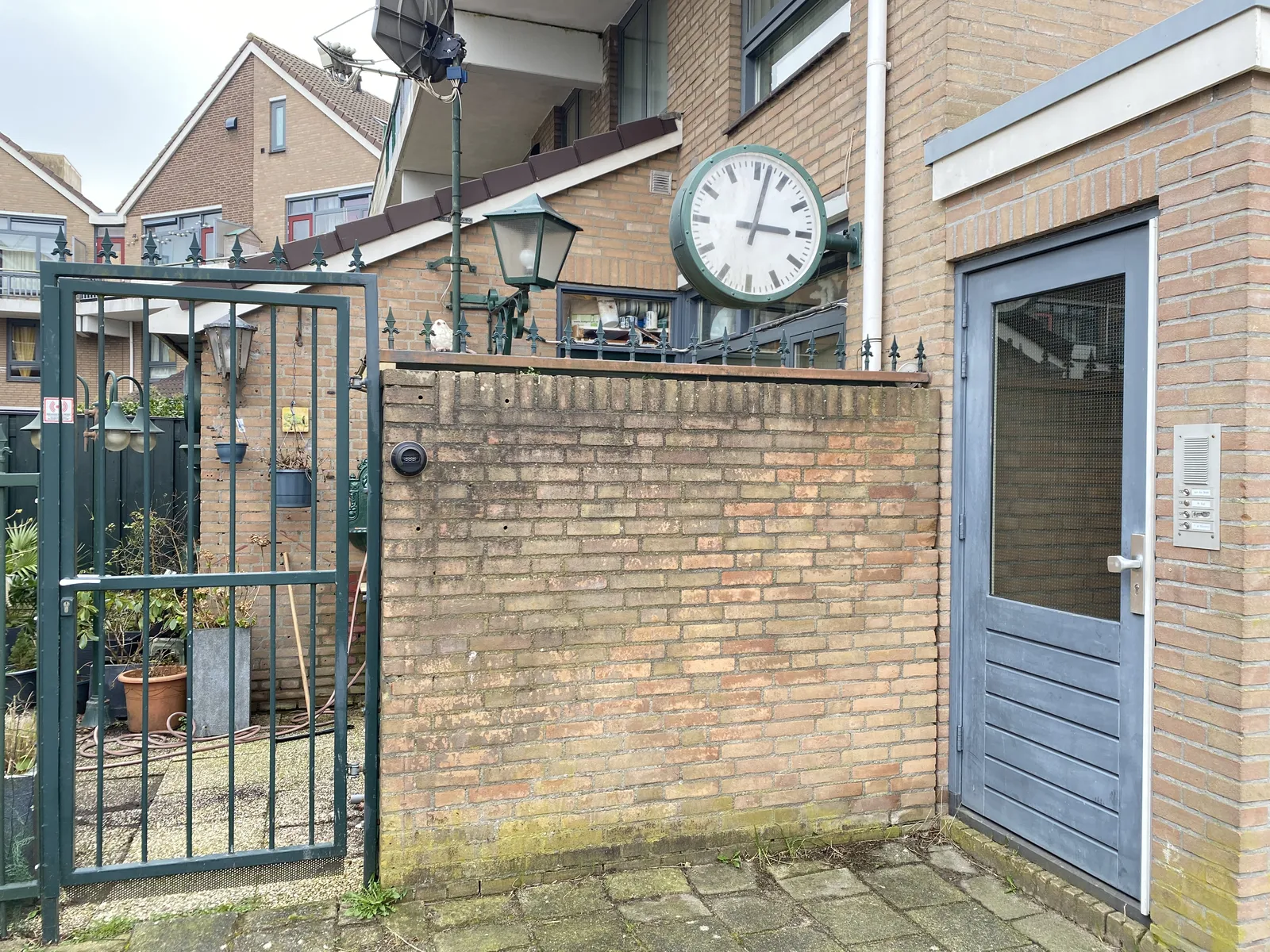 You would expect such a clock in a train station, and not in the backyard of a typical dutch housing block. Yet there it is. It points at 2 minutes past 3.  