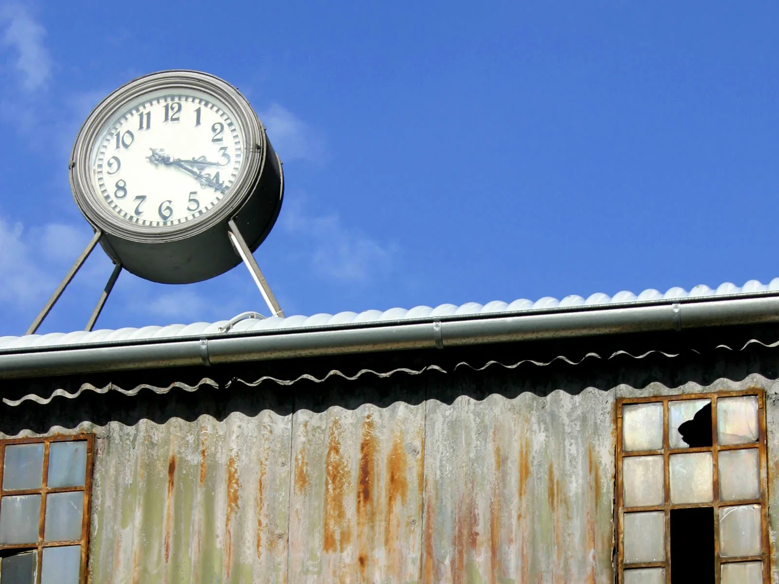 A clock on a industrial roof. It says it is 15:20