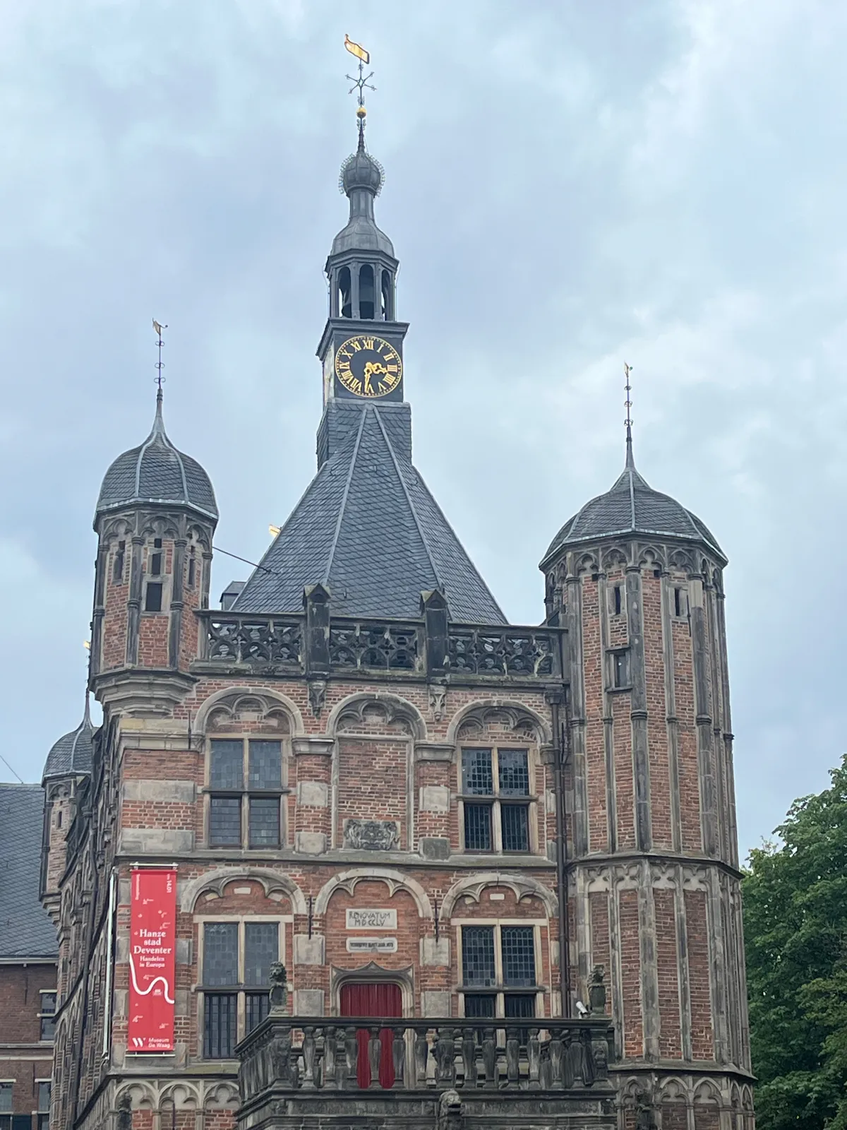 A clock on a medieval looking building in Deventer. On its tower there’s a clock. It points at 31 minutes past 3.