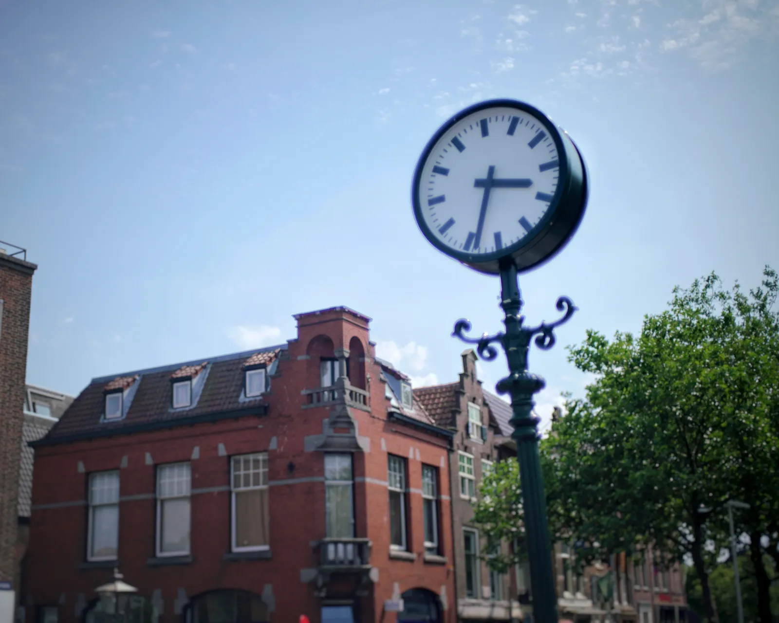 A clock on a pole in a city. It points at 33 past 3.
