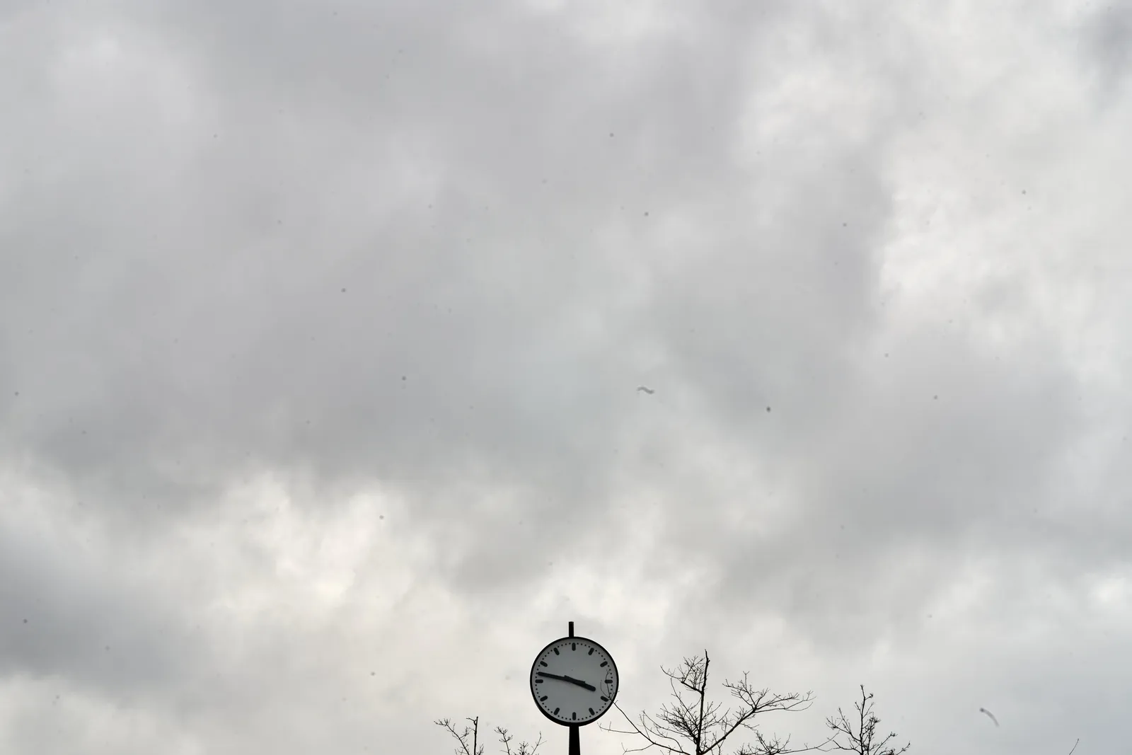 Cloudy weather. There’s a clock that points at 13 minutes to 4.