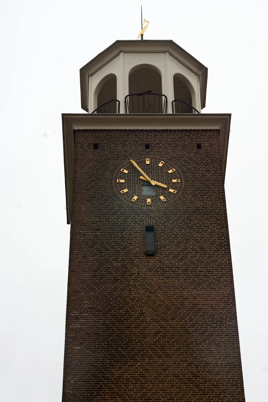 A solid church tower, with a small white, round room on top, with windows looking in all directions. There’s also a clock on this tower. It points at 15:55. 
