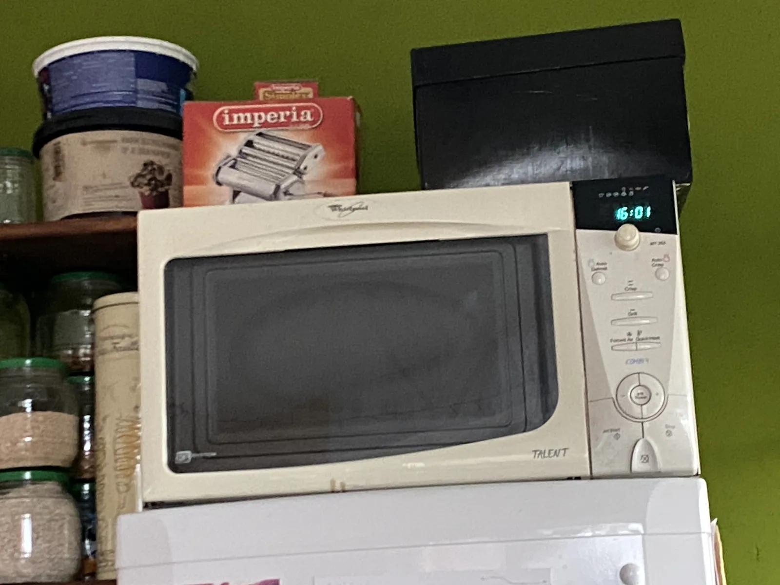 A digital clock on a small microwave prints the time as 16:01. 