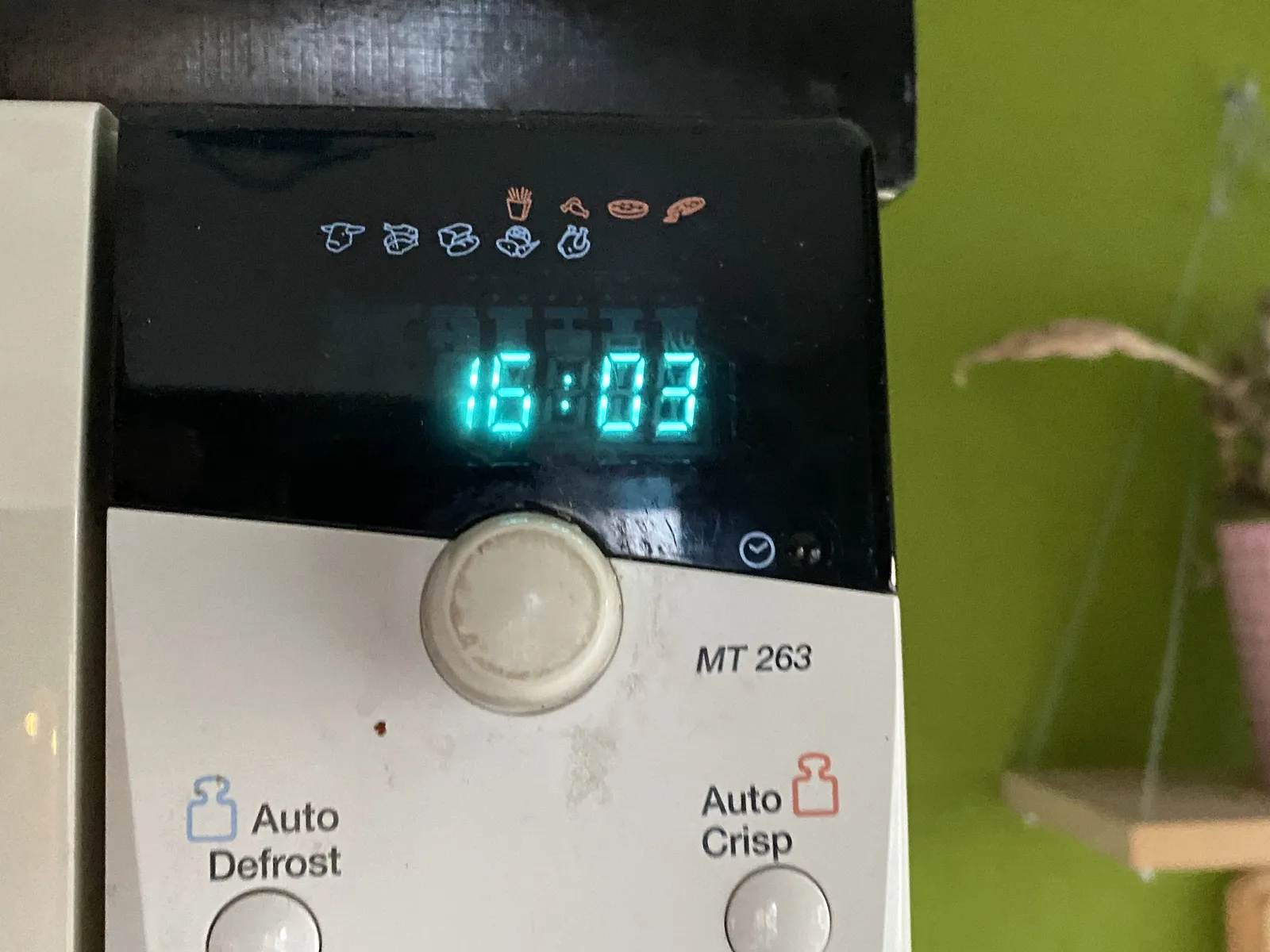 A close-up of a digital clock on a microwave. It is 16:03.