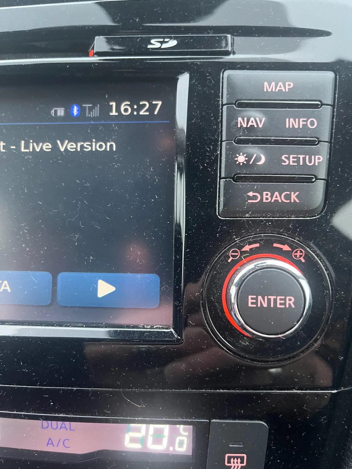 Buttons, knobs and part of a display of a car stereo. On this display you can see that it is 16:27.