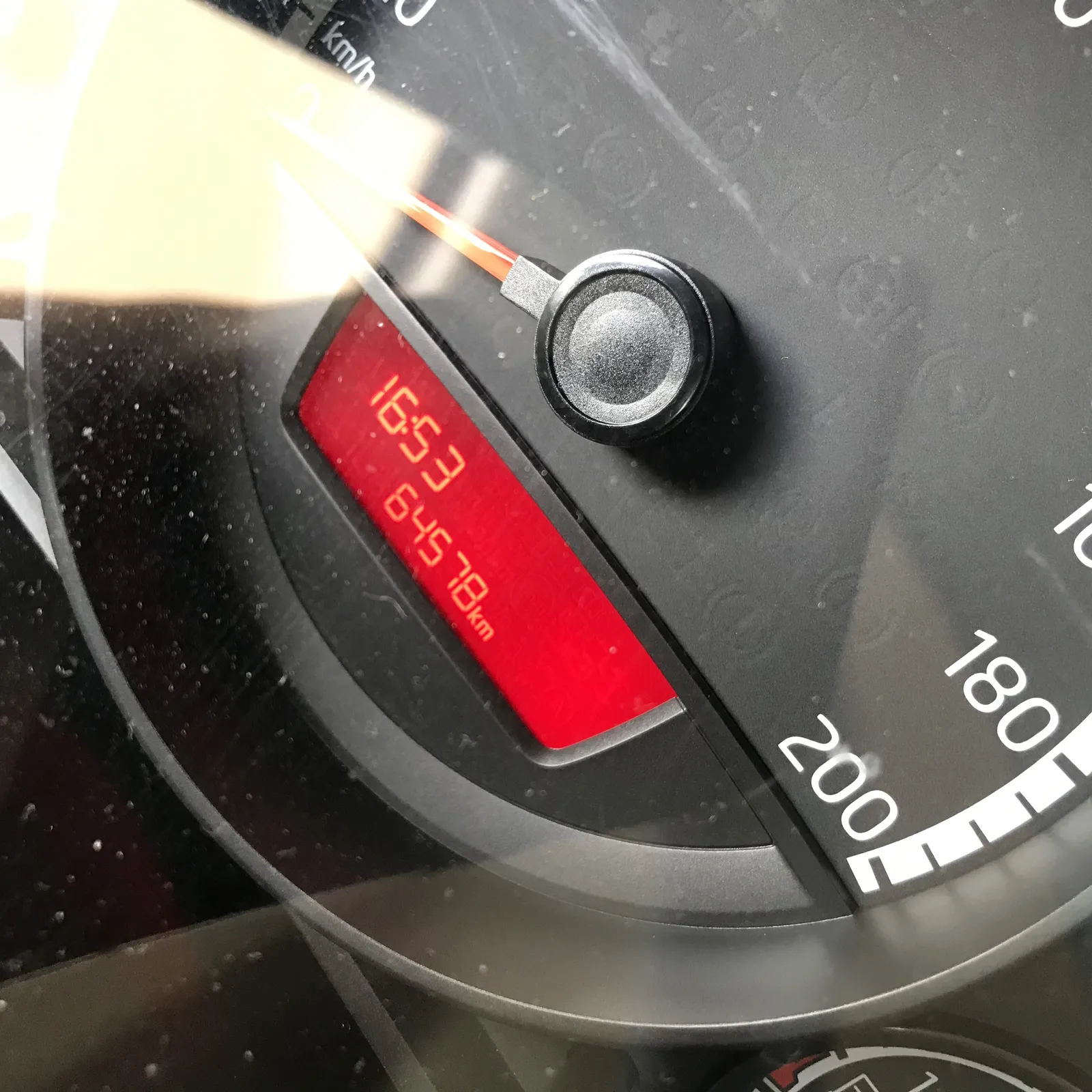 The speedometer of a car points at zero. The car has driven 64578 kilometers so far, and the digital clock says it is 16:53