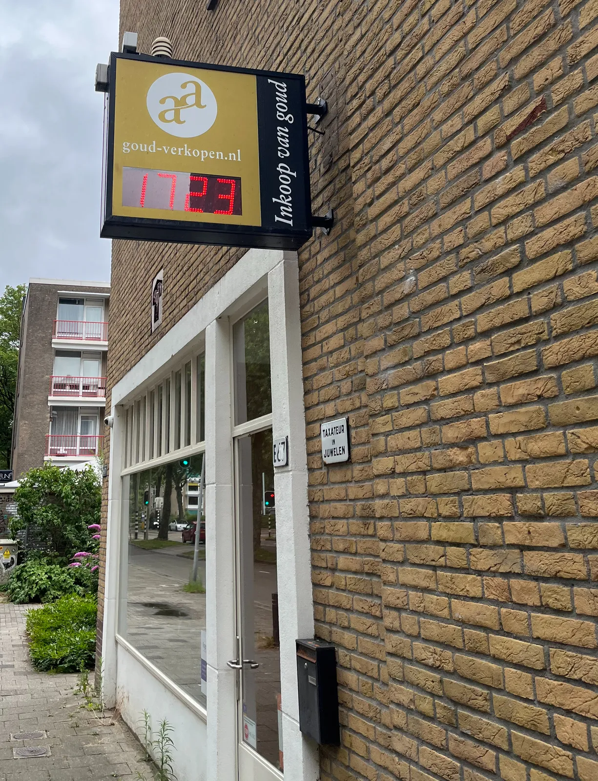 Attached to a store that buys and sells gold there’s a digital clock that tells us that it is 23 minutes past 17.