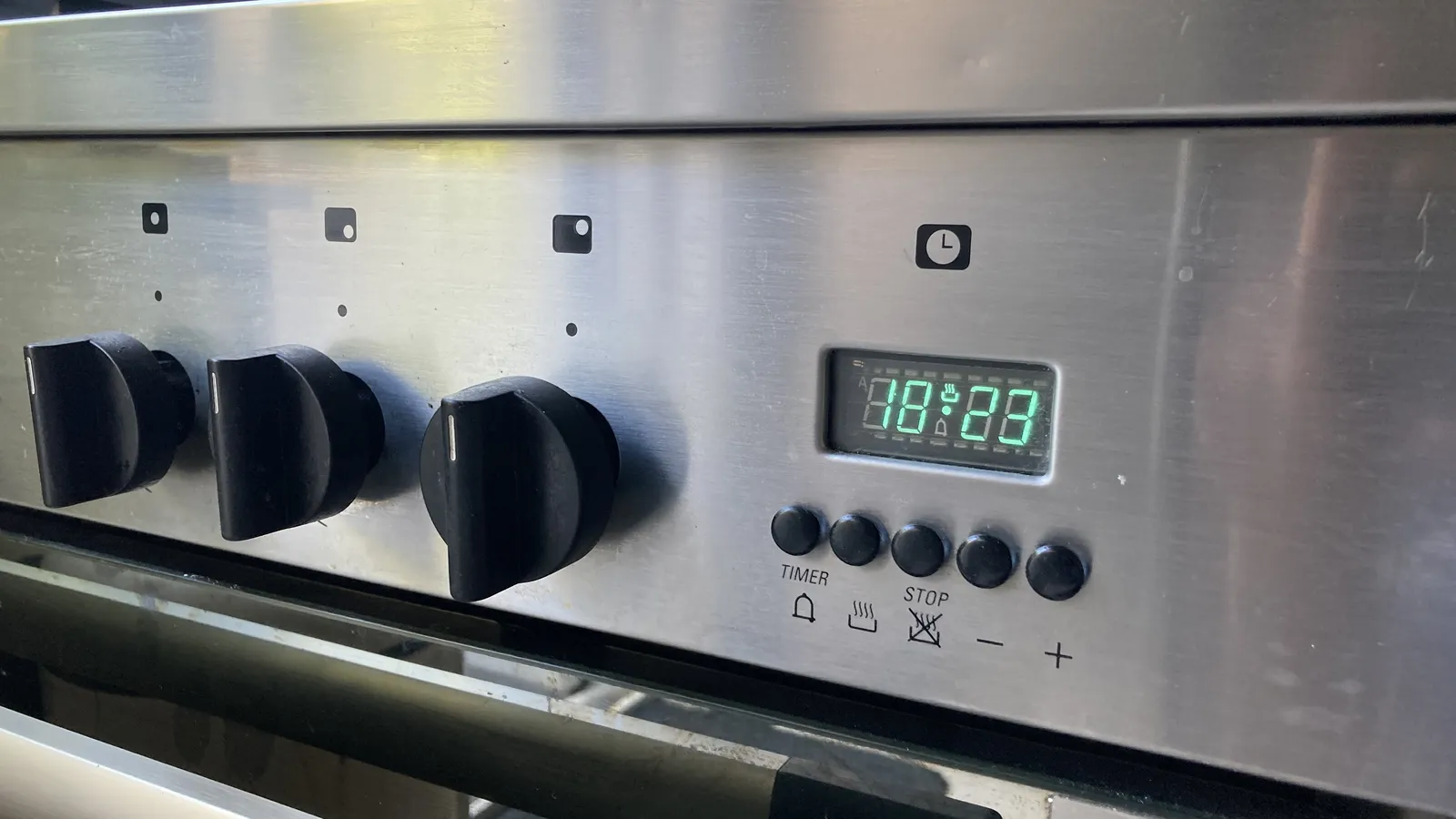 A digital clock on an oven. It says it is 18:23.