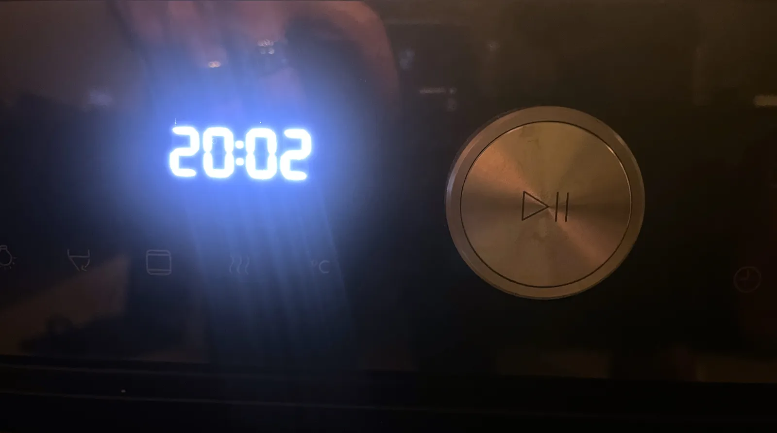 Next to a silver play pause button there’s a bright, digital clock that says it is 20:02