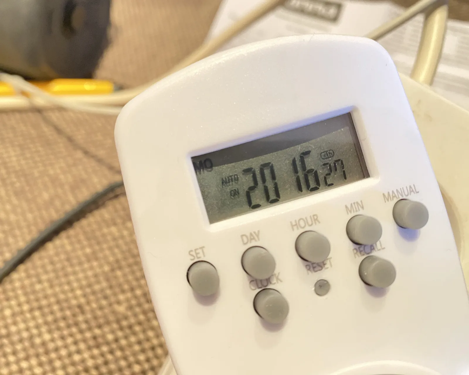 On a digital device with many small rubber buttons, it looks like one of those time switches, the display says it is 20:16.