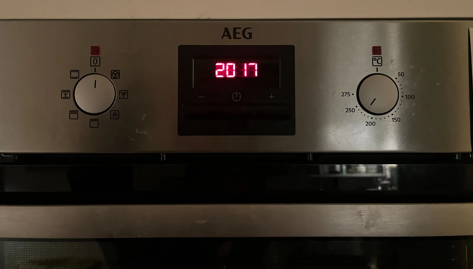 An AEG oven with two knobs, and between these knobs, a digital clock. It says it is 20:17