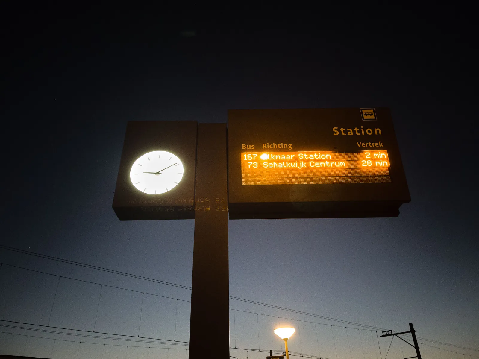 A lit billboard that shows how many minutes before the bus leaves. There’s a clock attached to this billboard that points at 9 minutes past 9