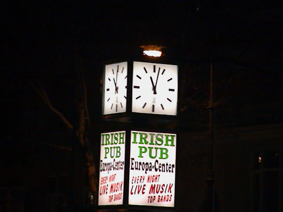 The clock above this sign that promotes an Irish Pub points at 3 past 11.