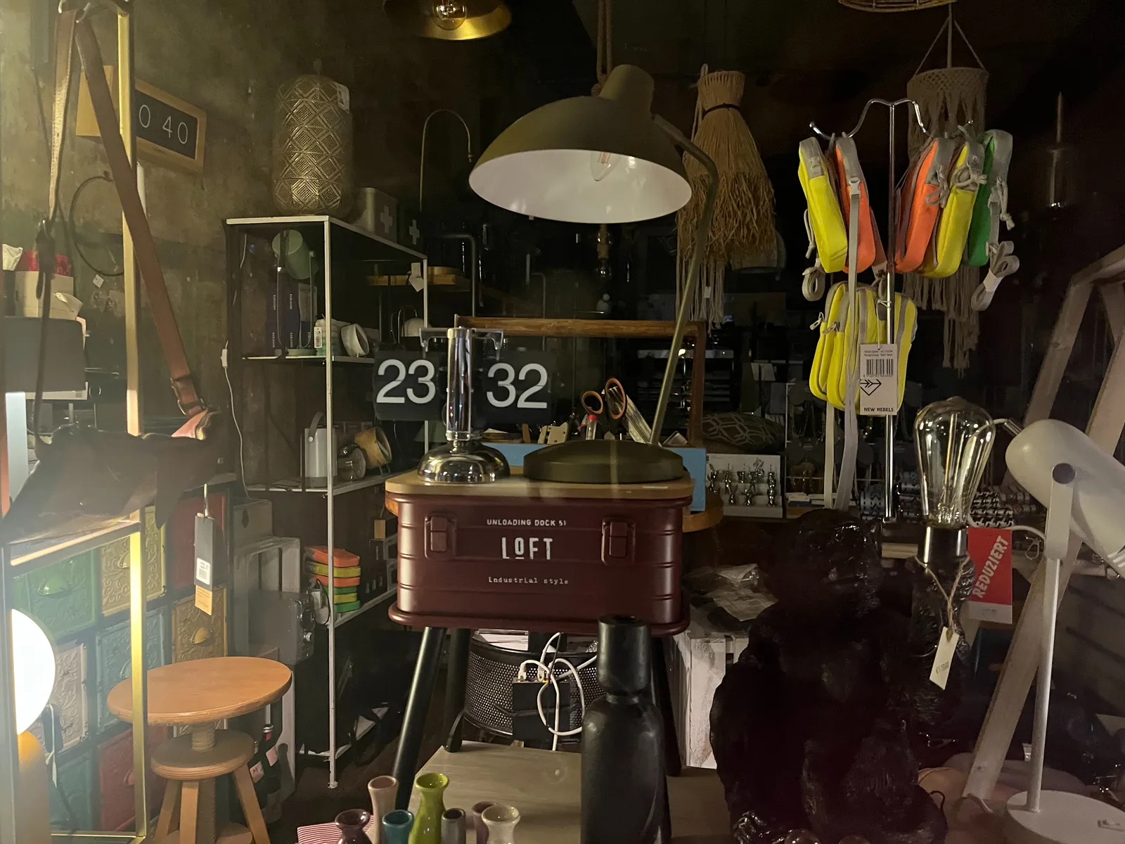 All kinds of stuff for sale in this shop. Among the stuff is a clock with a flipping mechanism that shows that right now it is 23:32.