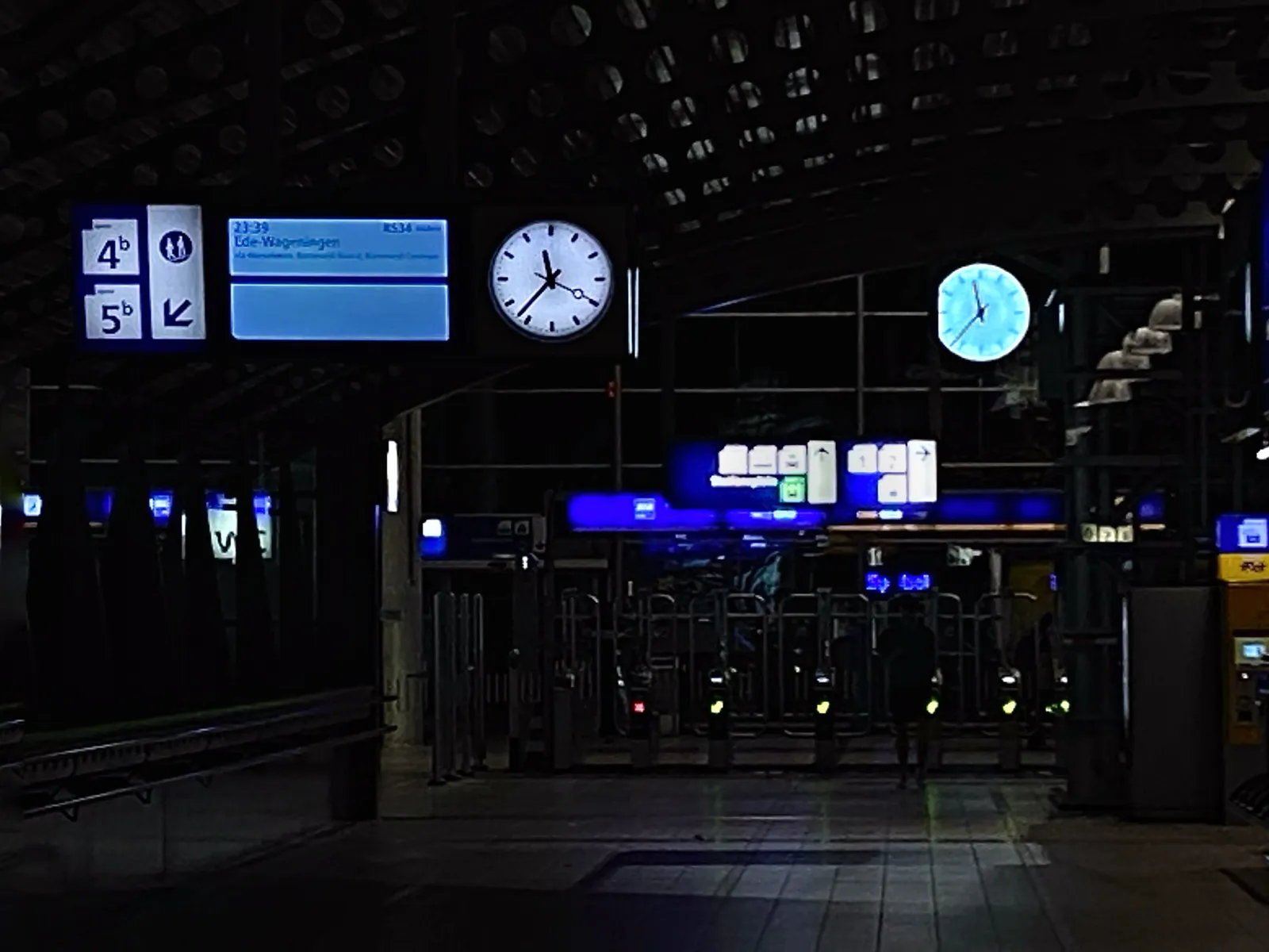 A dark, nightly train station with two lit clocks. They both point at 37 minutes past 11.