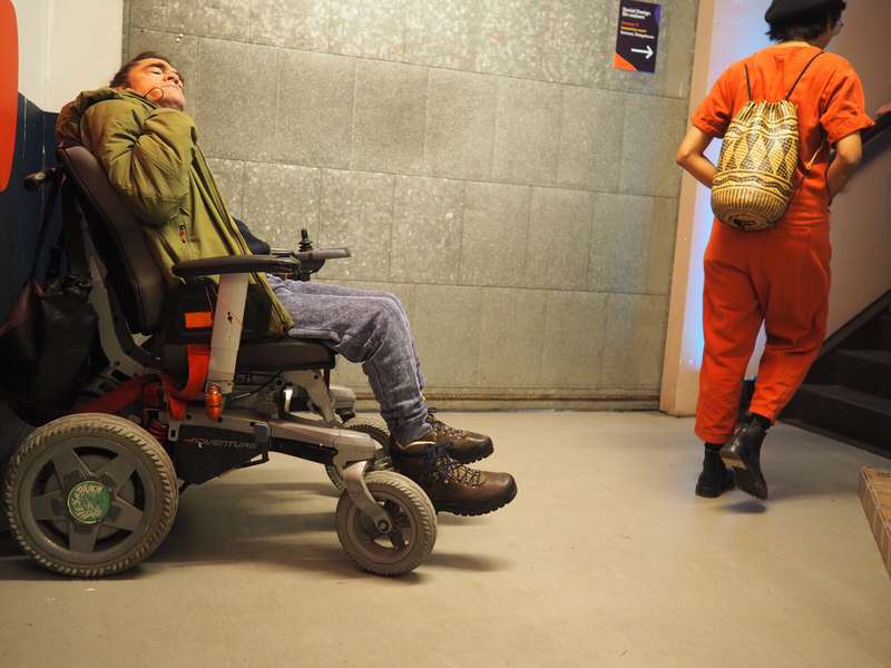 Marijn sits in his chair while another visitor walks up the stairs.