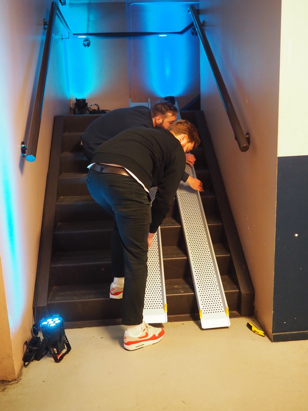 Two people are placing guiding rails onto the stairs