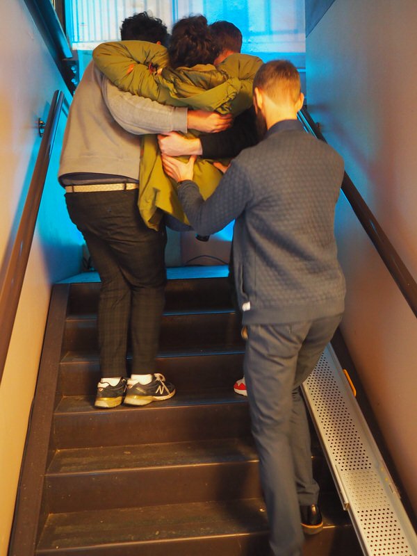 Three people are lifting Marijn up the stairs